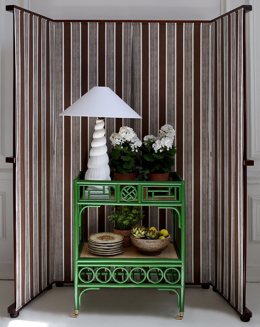 Green side table with decorative items against a striped room divider.